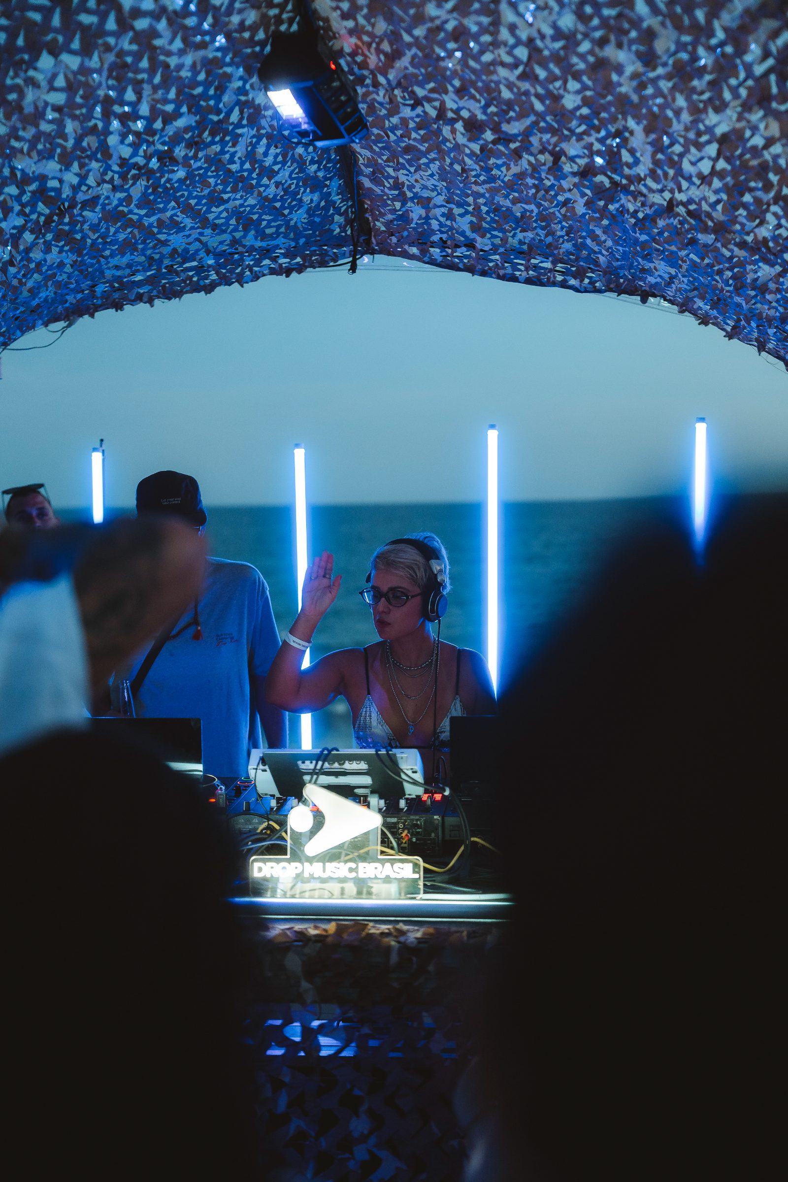 Cabine de DJ da Drop com luzes neon e o mar ao fundo